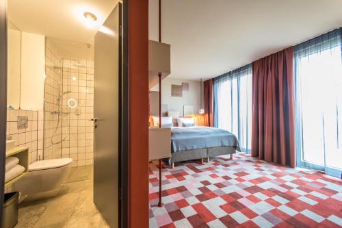 a hotel room with a bed and a bathroom at Hotel einsmehr in Augsburg
