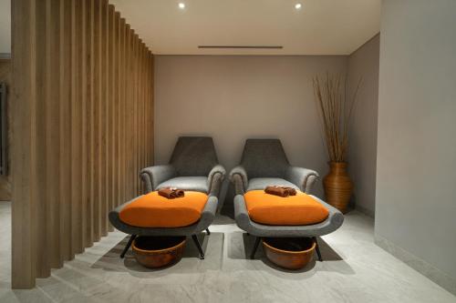 two chairs with orange cushions in a waiting room at Harris Suites Puri Mansion in Jakarta