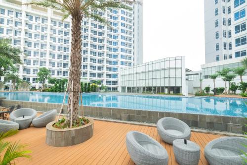 um resort com uma palmeira e cadeiras e uma piscina em Harris Suites Puri Mansion em Jakarta