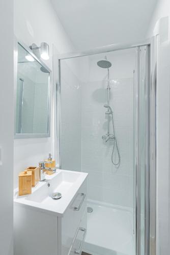 une salle de bain blanche avec une douche et un lavabo dans l'établissement Vence... un goût d'ailleurs, à Vence