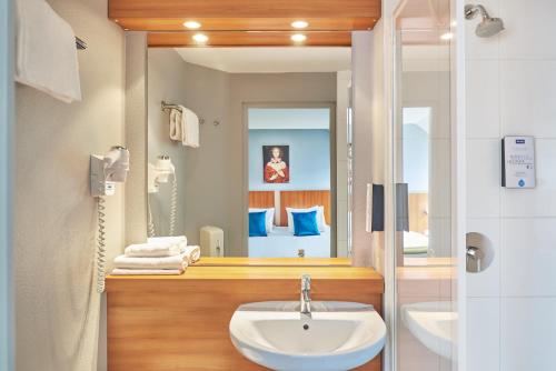 La salle de bains est pourvue d'un lavabo et d'un miroir. dans l'établissement Kyriad Paris Sud Les Ulis Courtaboeuf, aux Ulis