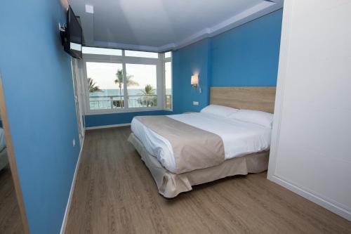 a bedroom with a bed with blue walls and a window at Luxury Ocean Beach Apartment in Altea