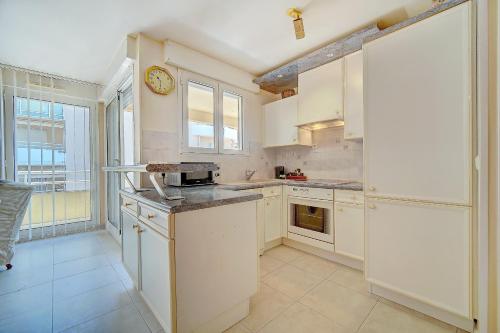 une cuisine avec des placards blancs et une horloge murale dans l'établissement IMMOGROOM - Terrace - Bright - Heart of Cannes - Parking, à Cannes