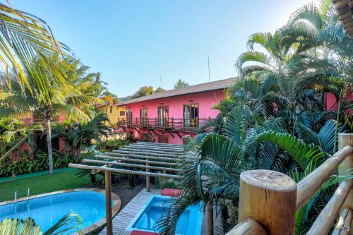 a resort with a pink building and a swimming pool at Pousada Vira Canoa in Itacaré