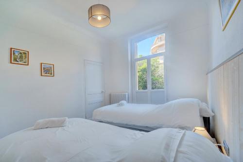 deux lits dans une chambre blanche avec une fenêtre dans l'établissement IMMOGROOM - Suquet - 2 min from the beaches, à Cannes