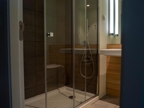 a glass shower in a bathroom with a sink at Flag Hotel Caldas da Rainha in Caldas da Rainha