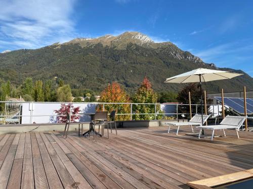 a deck with chairs and an umbrella and a mountain at Sky Garden & Wellness R. in Belluno