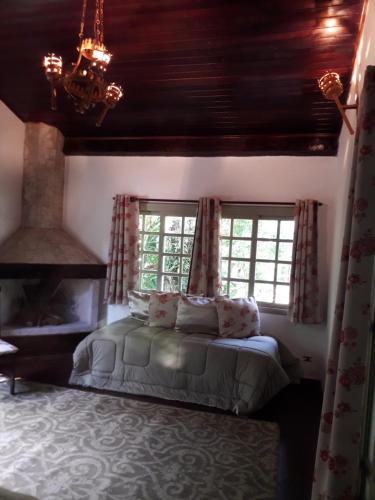um quarto com uma cama com janelas e uma lareira em Casa Linda - Piscina Ampla - Jacuzzi - Imenso Jardim em São Sebastião