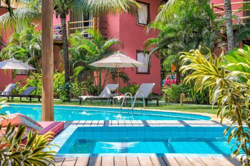 a swimming pool in front of a pink building at Pousada Vira Canoa in Itacaré