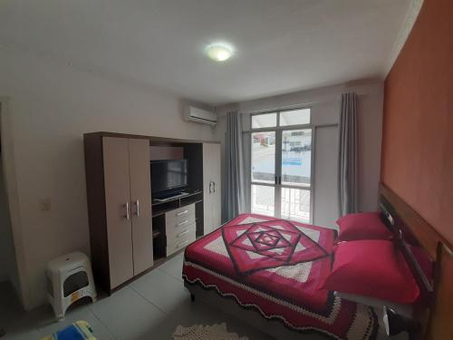 um quarto com uma cama, uma televisão e uma janela em Apto compacto em Floripa-continente em Florianópolis