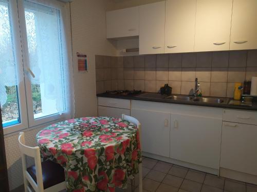 une cuisine avec une table et un tissu de table fleuri dans l'établissement Chez Fabienne T1, à Le Breuil-sur-Couze