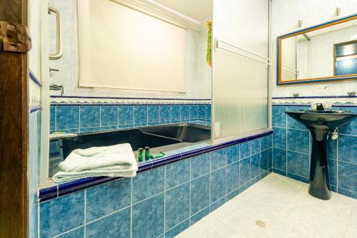 Baño de azulejos azules con lavabo y espejo en Hotel Ayenda Eclipse 1706 en Villavicencio