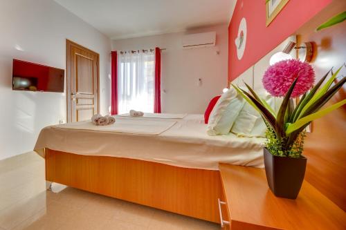 a bedroom with a large bed with a potted plant at Aparthotel Villa Primafila in Ulcinj