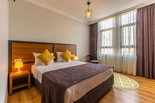 a hotel room with a large bed with yellow pillows at Antalya Business Hotel in Antalya
