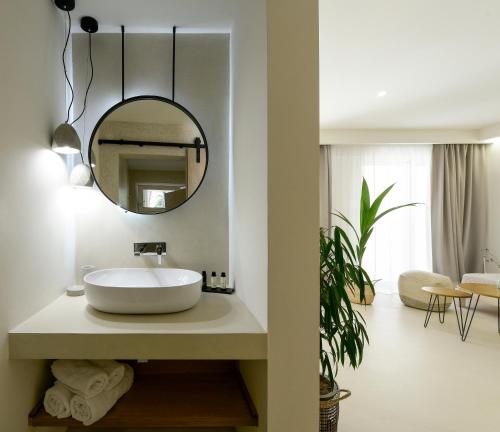 a bathroom with a white sink and a mirror at Karidi Beach Boutique Suites in Vourvourou