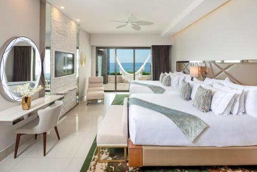 a hotel room with three beds and a mirror at Garza Blanca Resort & Spa Los Cabos in Cabo San Lucas