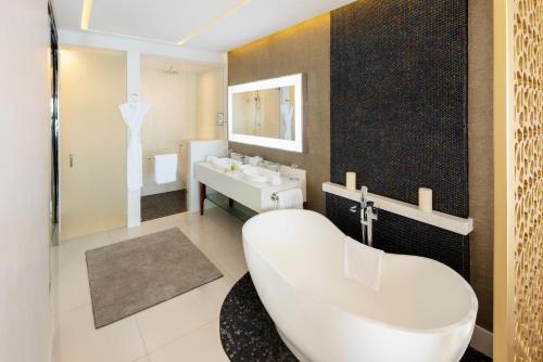 a bathroom with a large tub and a sink at Garza Blanca Resort & Spa Los Cabos in Cabo San Lucas