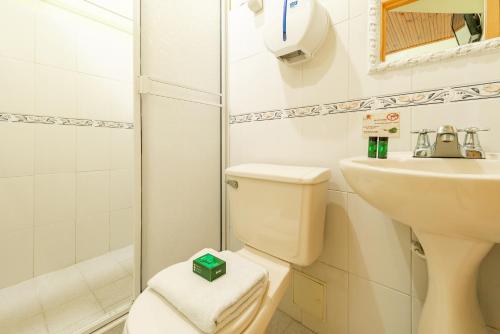 a white bathroom with a toilet and a sink at Eclipse Villavicencio in Villavicencio