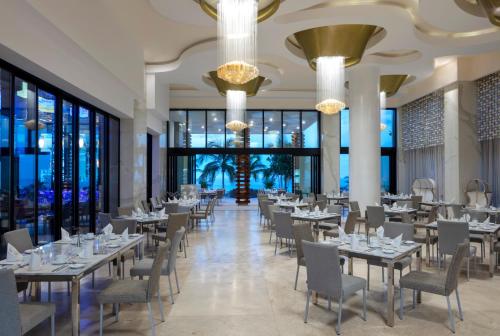 una sala da pranzo con tavoli, sedie e ampie finestre di Garza Blanca Resort & Spa Los Cabos a Cabo San Lucas