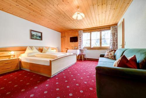 a bedroom with a large bed and a couch at Café Pension zum Jäger in Buchboden