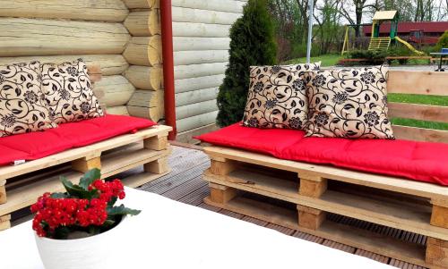 a porch with two benches with red cushions at Viesu nams Zaļā Sala in Litavniki