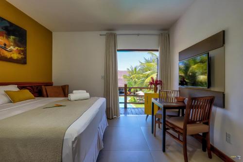 a hotel room with a bed and a desk and a window at Pousada Vira Canoa in Itacaré