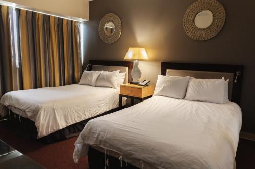 a hotel room with two beds and a table with a lamp at Stamford Suites in Stamford