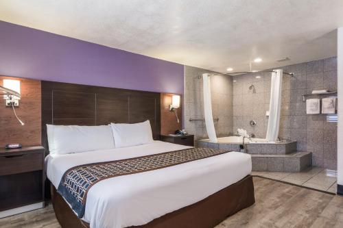 um quarto de hotel com uma cama grande e uma banheira em Rodeway Inn near Downtown Monterey em Monterey