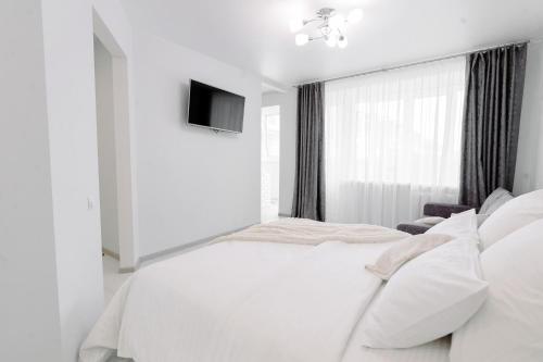 PaulMarie Apartments on Gor'kogo 41 في بابرويسك: غرفة نوم بيضاء فيها سرير وتلفزيون