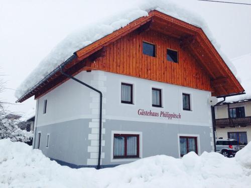 un edificio con techo rojo en la nieve en Haus Philippitsch, en Rattendorf