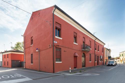 a red building on the side of a street at Dimora Tipica Ferrarese in Ferrara