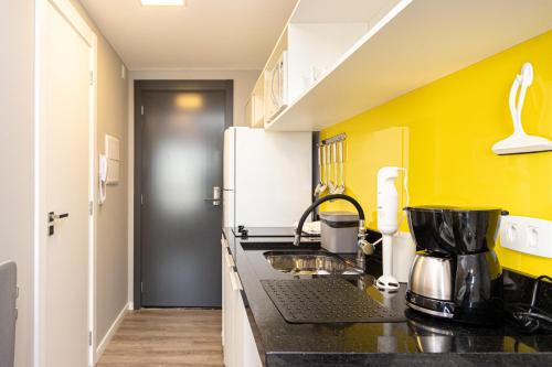 a kitchen with a black counter and yellow walls at Welcome CWB - AYN037 in Curitiba