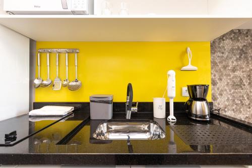 a kitchen with a sink and a yellow wall at Welcome CWB - AYN037 in Curitiba