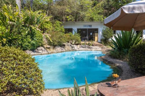 a large blue pool in a yard with a table at Pousada Estalagem da Villa in Casa Branca