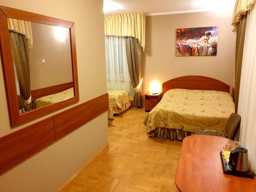 ein Hotelzimmer mit einem Bett und einem Spiegel in der Unterkunft Pałac pod Dębami in Zalasowa