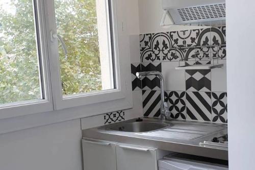 une cuisine avec un évier et une fenêtre dans l'établissement Appartement - Cosy T1 bis, proche de Paris, à Villeneuve-la-Garenne