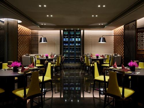 a dining room with tables and yellow chairs at InterContinental Shanghai Wonderland by IHG in Songjiang