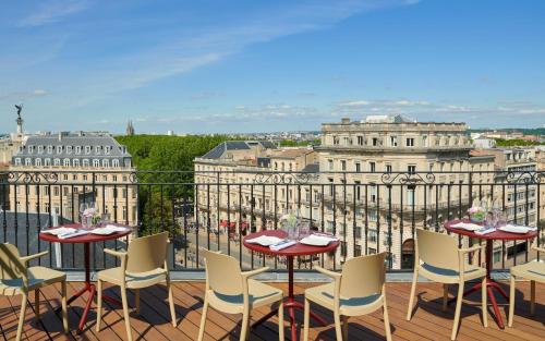 a balcony with tables and chairs and a view of the city at InterContinental Bordeaux Le Grand Hotel by IHG in Bordeaux