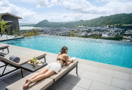 a woman laying on a bench next to a swimming pool at ANA InterContinental Beppu Resort & Spa by IHG in Beppu