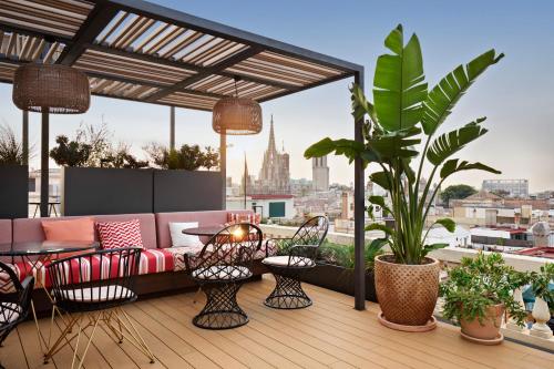 un patio all'ultimo piano con divano, tavoli e piante di Kimpton Vividora Hotel, an IHG Hotel a Barcellona