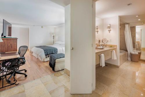 a bedroom with a bed and a desk and a bathroom at Presidente InterContinental Puebla by IHG in Puebla