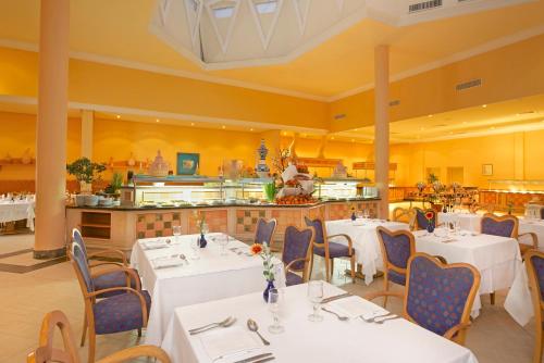 a restaurant with white tables and chairs and a kitchen at Vincci Saphir Palace & Spa in Hammamet