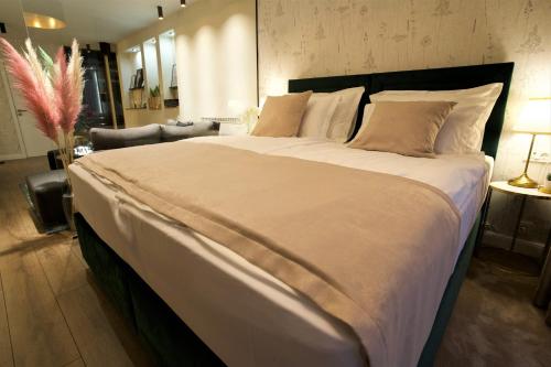 een groot bed met witte lakens en kussens in een slaapkamer bij Apartman My Story in Osijek