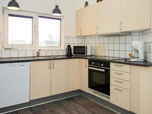eine Küche mit weißen Schränken und schwarzen Arbeitsplatten in der Unterkunft 8 person holiday home in Ringk bing in Søndervig