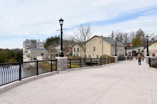 a bridge over a river with a person walking on it at Staybridge Suites - Waterloo - St. Jacobs Area in Waterloo