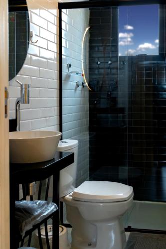 a bathroom with a toilet and a sink and a shower at Castro's Hotel in Telêmaco Borba