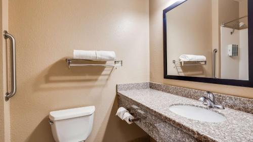a bathroom with a sink and a toilet and a mirror at Best Western El-Quartelejo Inn & Suites in Scott City