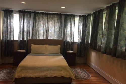 a bedroom with a bed with curtains and windows at 3 Bedroom Apartment steps to Clifton, Zoo, UC, Hospitals in Cincinnati