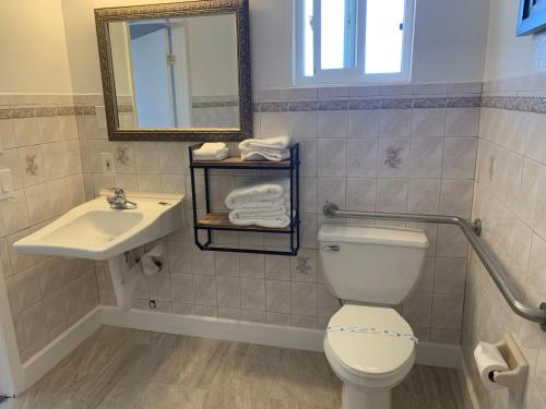 een badkamer met een toilet, een wastafel en een spiegel bij Travelers Inn in South San Francisco