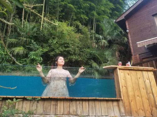 une femme debout en face d'une piscine dans l'établissement Mogan Mountain Xiaomusensen, à Deqing